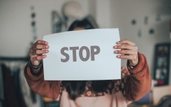 A child holding a paper that says Stop for child abuse. GettyImages/Carol Yepes