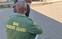 A border guard checking a woman's credentials. eNCA