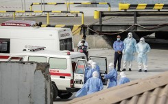 Health personnel returning from the cruise ship MV Hondius, are seen at the port of Praia, the capital of Cape Verde, as individuals wearing hazmat suits are helped into an ambulance on May 6, 2026.