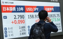 A man walks past an electronic quotation board displaying 10-year Japanese government bonds. AFP/Kazuhiro Nogi