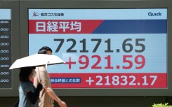 Pedestrians walk past an electronic quotation board displaying the Nikkei Stock Average on the Tokyo Stock Exchange in Tokyo. AFP