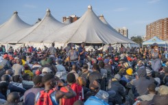 Police officers keep order as hundreds of newly displaced foreign nationals take refuge at the old Durban Drive Inn in Durban. AFP/Rajesh Jantilal