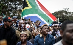 Members of the Zulu regiment known as the ‘Amabutho’ hold a South African flag as they march during a demonstration by the "March and March" movement. AFP/Marco Longari