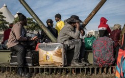 Undocumented migrants line up for transport to their home countries. AFP/Marco Longari