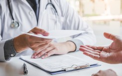  Doctor or physician writing diagnosis and giving a medical prescription to male Patient. Getty Images SARINYAPINNGAM