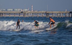 Surfers catch a wave at Venice Beach in Los Angeles, California. AFP/Apu Gomes
