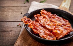 Hot fried crispy bacon slices in a skillet. GettyImages/LumenSt