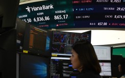 A dealer works near a screen showing South Korea’s benchmark KOSPI stocks index. AFP/Greg Baker