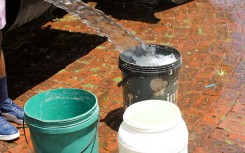 Buckets being filled with water from a water tanker.
