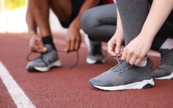 File:  Runners tying shoelaces of their sneakers. GettyImages/Olga Yastremska