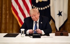 Former US president Donald Trump, holding a debit card during a 2020 cabinet meeting, has broad dicretion to spend campaign funds on legal bills