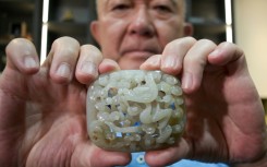 Chang Juben, chairman of Taiwan's Association of Jade Collectors, shows a Yuan dynasty jade belt ornament featuring a carving of a dragon among clouds