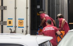 Morgue workers move a body bag into a refrigerated storage container adjacent to the Maui police department's forensic facility, where human remains are stored in the aftermath of the Maui wildfires