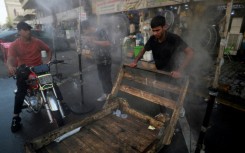 Men cool off with a mist dispenser set up in a street in central Baghdad amid soaring temperatures