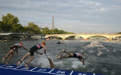 Athletes dive into the Seine River on Friday for the men's 2023 World Triathlon pre-Olympic test event