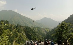 Anxious locals watch as a helicopter flies near the stranded cable car in northern Pakistan