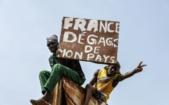 A man burns holds a placard reading 'France get out of my country' 
