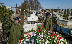 Soldiers stand guard as people lay wreaths  during a ceremony at the grave of The Ulma family