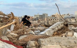 People sit among the rubble in Libya's eastern city of Derna