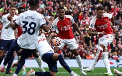 Tottenham's Cristian Romero (C) blocks Ben White's shot with his hand