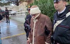 This handout video grab taken and released by the Italian Carabinieri Press Office on January 16, 2023 shows the transfer of mafia boss Matteo Messina Denaro (C) to an undisclosed location following his arrest