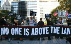 Protestors hold banners outside New York State Supreme Court ahead of the start of a civil fraud trial against Donald Trump