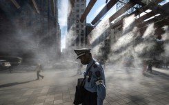 A security guard walks past an overhead water misting system on a hot day in Tokyo on July 10, 2023