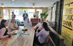 US Federal Reserve Chairman Jerome Powell and Patrick T. Harker, president and CEO of the Philadelphia Federal Reserve (2R), meet with residents during a visit to York, Pennsylvania, on October 2, 2023
