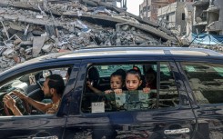 Palestinians drive amid the rubble of buildings destroyed in an Israeli air strike in Rafah, on the southern Gaza Strip 