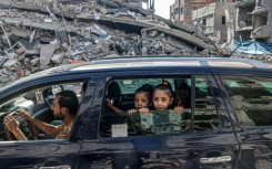 Palestinians drive amid the rubble of buildings destroyed in an Israeli air strike in Rafah, on the southern Gaza Strip 