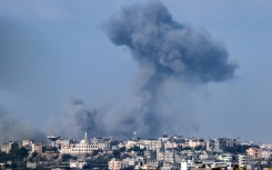 This aerial view shows people standing before destroyed buildings at the site of the Ahli Arab hospital in central Gaza on October 18, 2023 in the aftermath of an overnight strike there. 