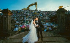 Iris Hsueh (L) and her fiance Ian Ciou take a wedding photo in front of a huge mound of garbage in Puli township, Taiwan