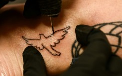 Tattoo artist Kat Dukes inks a hand poked tattoo of a dove on Scout Frank using ink mixed with the ashes of Frank’s cremated mother in Oceanside, California on October 6, 2023