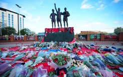 Floral tributes are pictured at the base of the 'United Trinity' statue, depicting former Manchester United players George Best, Denis Law and Bobby Charlton