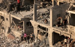 People search for survivors and the bodies of victims through buildings that were destroyed during Israeli bombardment, in Khan Yunis in the southern Gaza Strip on October 25, 2023