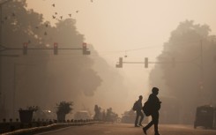 Commuters cross a street amid smoggy conditions in New Delhi in November 2021
