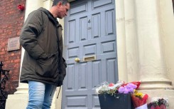 Brazilian Caio Benicio looks at flowers placed at the scene of the November 23 attack in Dublin