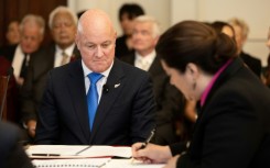 Christopher Luxon (L) looks on as Governor General Dame Cindy Kiro signs documents which formally made him Prime Minister of New Zealand on Monday 