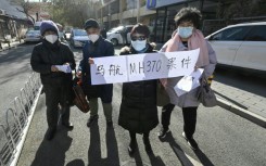 Relatives of passengers of the missing Malaysia Airlines flight MH370 hold a sign reading "Malaysia Airlines MH370 cases" close to a court building in Beijing
