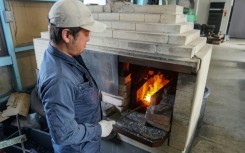 Yoshihiro Yauji, seen placing a piece of metal into a forge, believes 'blades are the foundational root of Japanese culture'