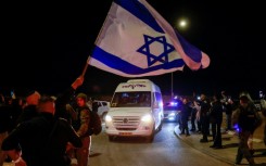 Supporters wave the Israeli flag as they wait for newly released hostages