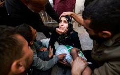 People try to comfort a woman holding the body of her baby girl killed in an Israeli strike in Rafah in the southern Gaza Strip
