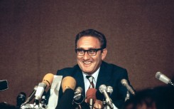 Henry Kissinger laughs during a press conference after the final communique on the Vietnam Peace Accords, signed by Kissinger and Le Duc Tho