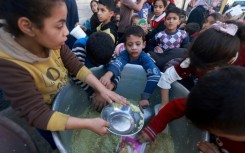 Palestinian children collect food at a donation point provided by a charity group in the southern Gaza city of Rafah