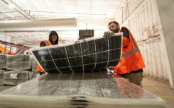 Workers push damaged solar panels into a machine to be recycled at the We Recycle Solar plant in Yuma, Arizona 