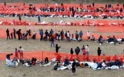 Migrants await processing by immigration authorities after crossing the US-Mexico border in Eagle Pass, Texas, December 20, 2023