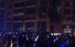 People gather in the street at site of explosion in Beirut's southern suburbs