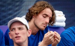 Greece's Stefanos Tsitsipas (R) sits on the team bench after pulling out of singles match at the United Cup