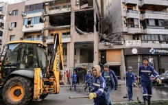 Municipal workers in Beirut clean the street in front of the building hit by a strike that killed Hamas deputy leader Saleh al-Aruri 