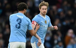 Manchester City's Ruben Dias (L) passes the captain's armband to Kevin De Bruyne
